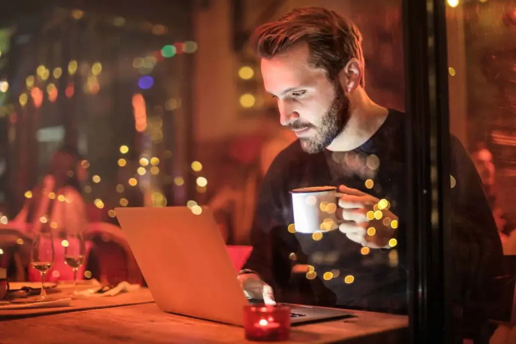 man looking at computer drinking coffee