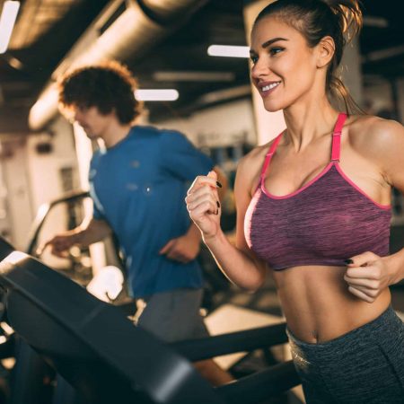 Horizontal photo of attractive woman jogging on treadmill at health club.